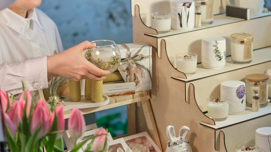 Local artisan craft at No.42, someone holding a bowl. There's a shelf showing a selection of candles and trinkets.