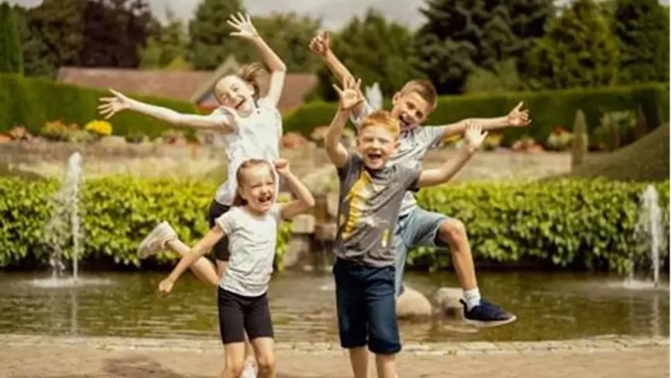 Four children jumping in the air in front of a pond at Durham University Botanic Garden.