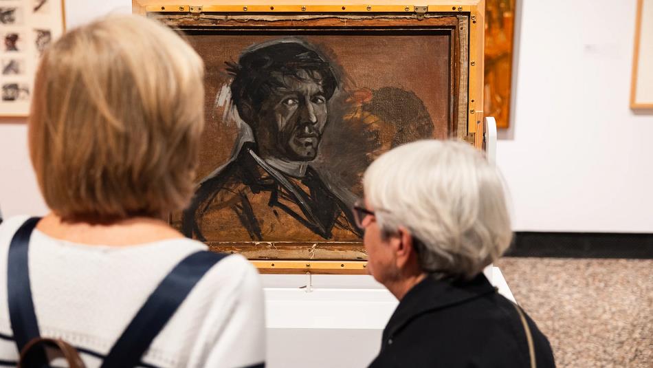 Two people admiring Norman Cornish's artwork.