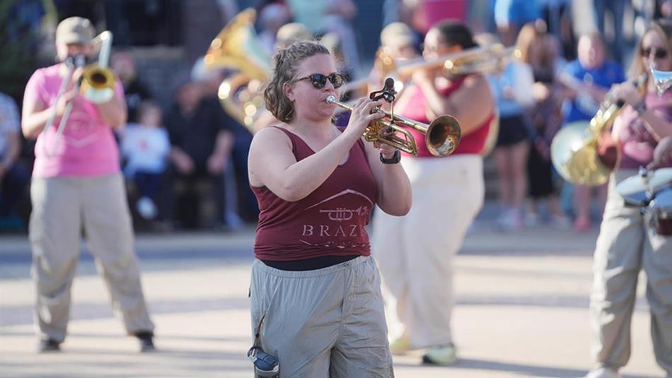 Members of brass bands playing to crowds in the streets.