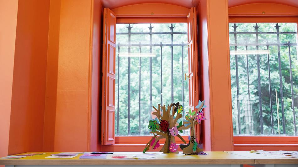 Flowers in front of a window that leads to a view of trees.