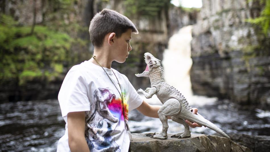 Child with dinosaur model at High Force Waterfall.