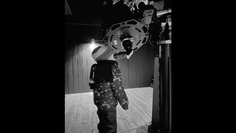 A young child looks through the eyepiece of a telescope.