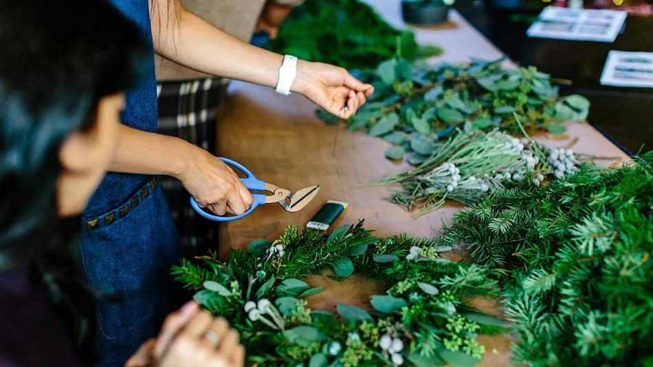 People making wreathes from festive greenery.