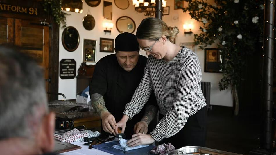 Peter Miskin showing a guest how to prepare seafood.