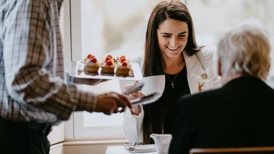 A woman smiling, whilst being served Easter Afternoon Tea at High Force Hotel