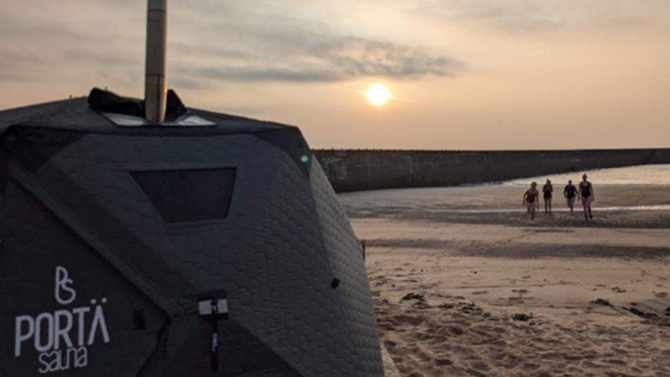 Beachgoers at sunrise on the beach in Seaham heading to the sauna