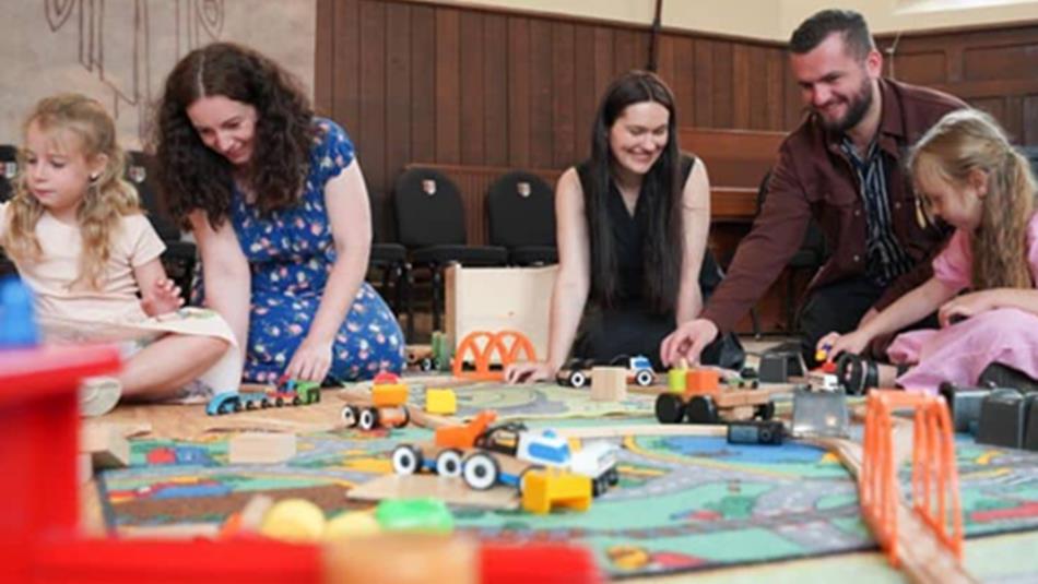 Adults and children playing with toy trains at Ushaw Historic House, Chapels and Gardens.