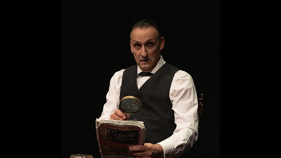 Sherlock Holmes reading a newspaper through a magnifying glass