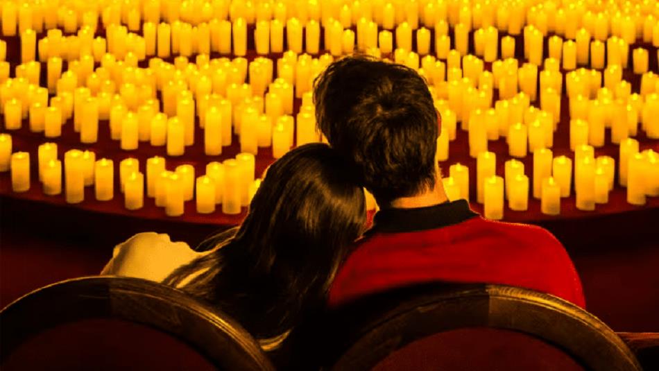 A couple resting their heads on each other, looking out onto hundred of candles.