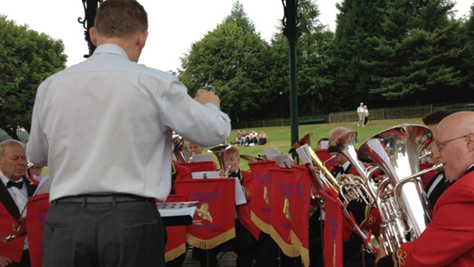 A brass band performing in the 1900s Town Bandstand at Beamish Museum with crowds watching.