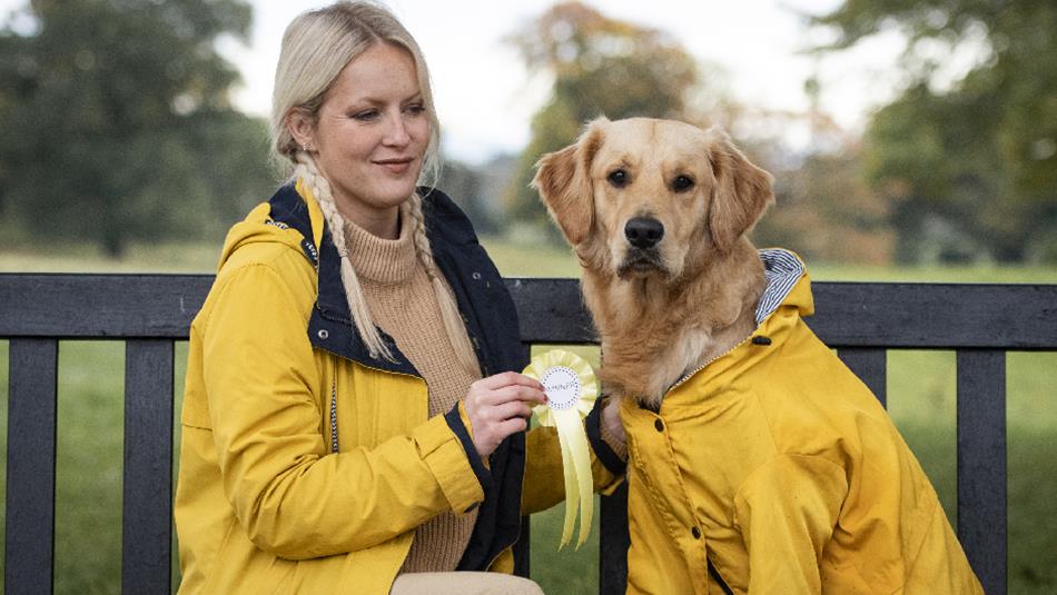 A woman sitting on a bench with a golden retriever in matching yellow coats