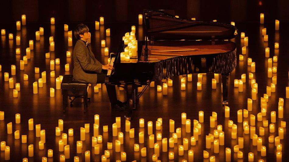Pianist performing amongst hundreds of candles.