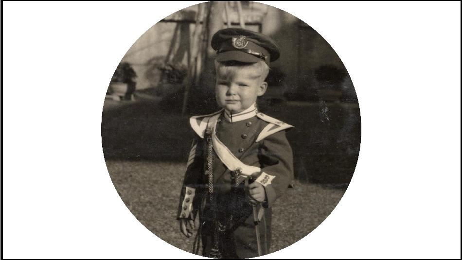 Black and white photo of a child in military clothing.