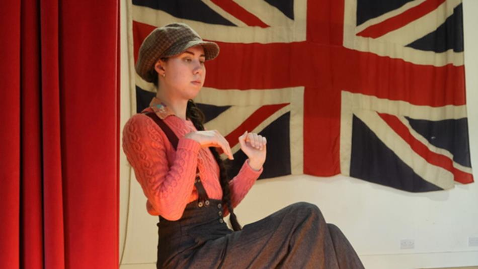 Actor in a cap in front of a Union Jack flag. Beamish Museum Pantomime 2026.