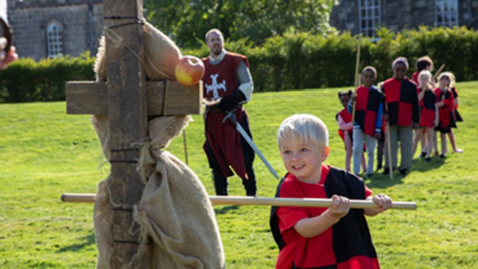 Children dressed as knights, holding wooden weapons.