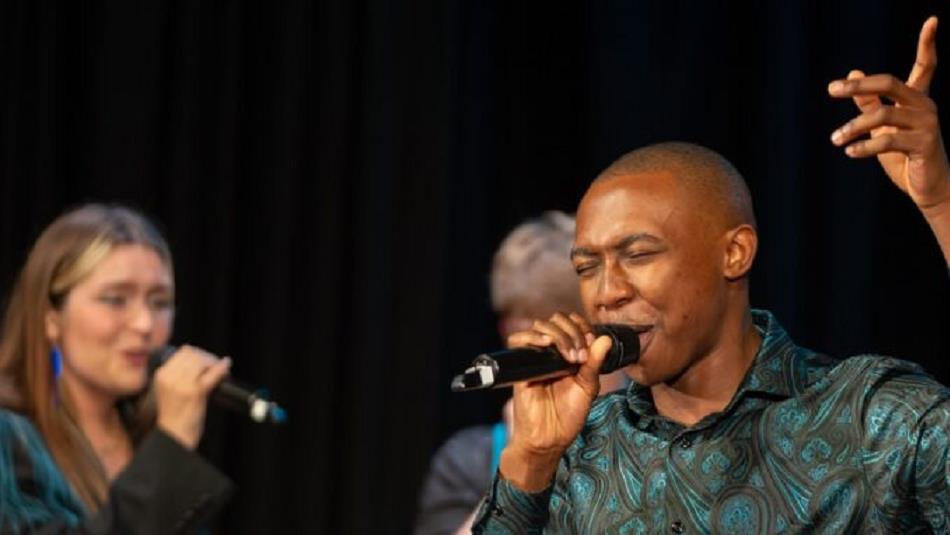 Three people singing on stage.