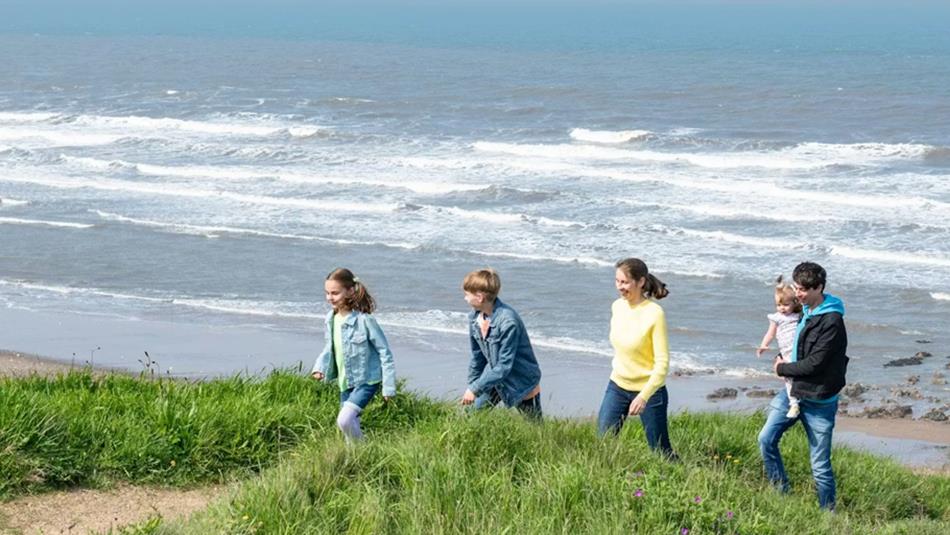 Five people enjoying a coastal walk along the grassy cliffs.