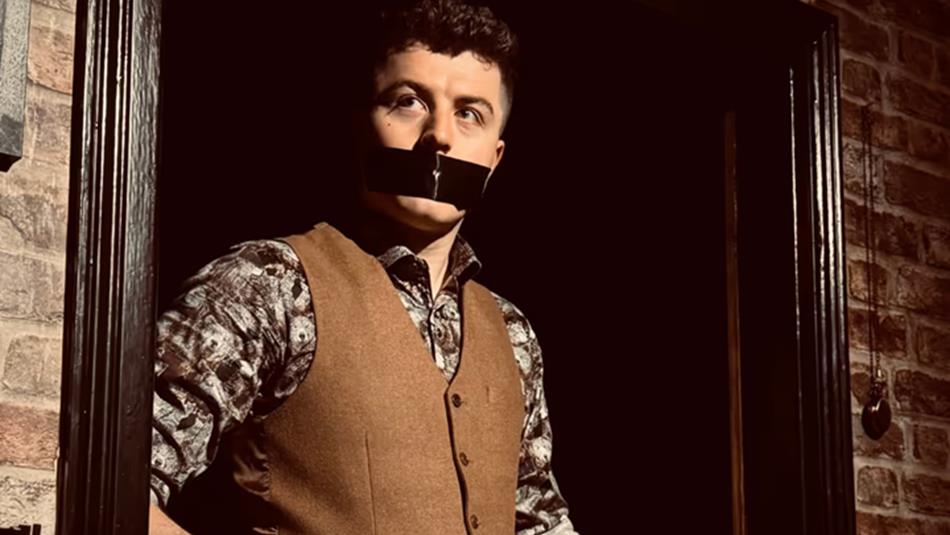 Tom Bolton with tape over his mouth.