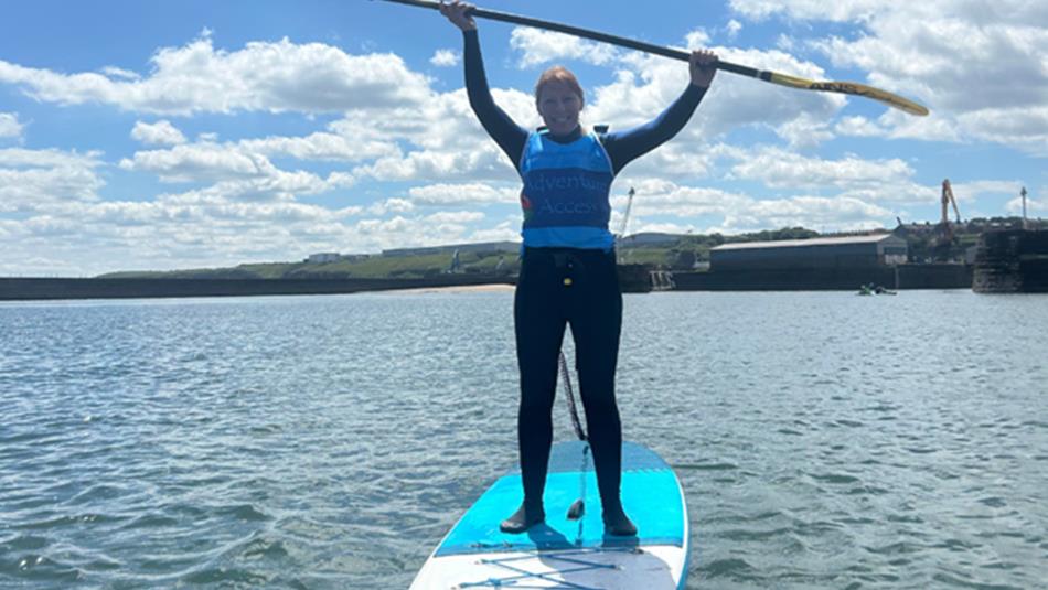SUP paddleboarder on the water with oar held above her head