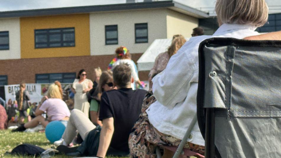 Crowds sitting on the lawn outside Bishop Auckland College.