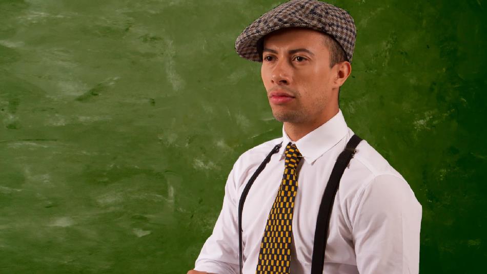 Someone wearing a flat cap and braces and chequerboard tie.