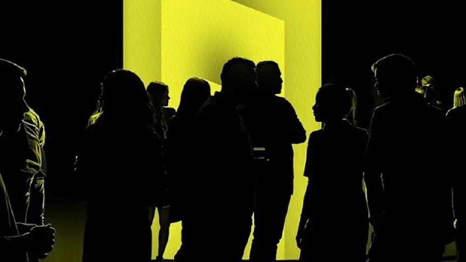 Silhouette of a crowd against a bright yellow light.