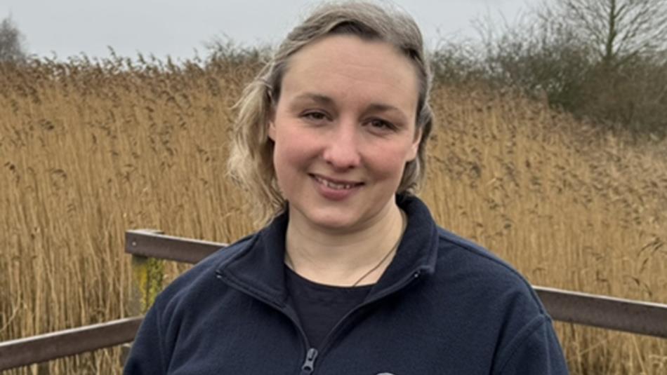 Dorinda Kealoha - Coastal Engagement Officer standing in front of a background of reeds.