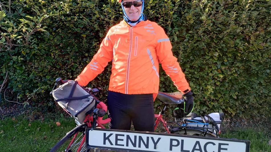 Ken Bradshaw with his bike outside of a street named 'Kenny Place'
