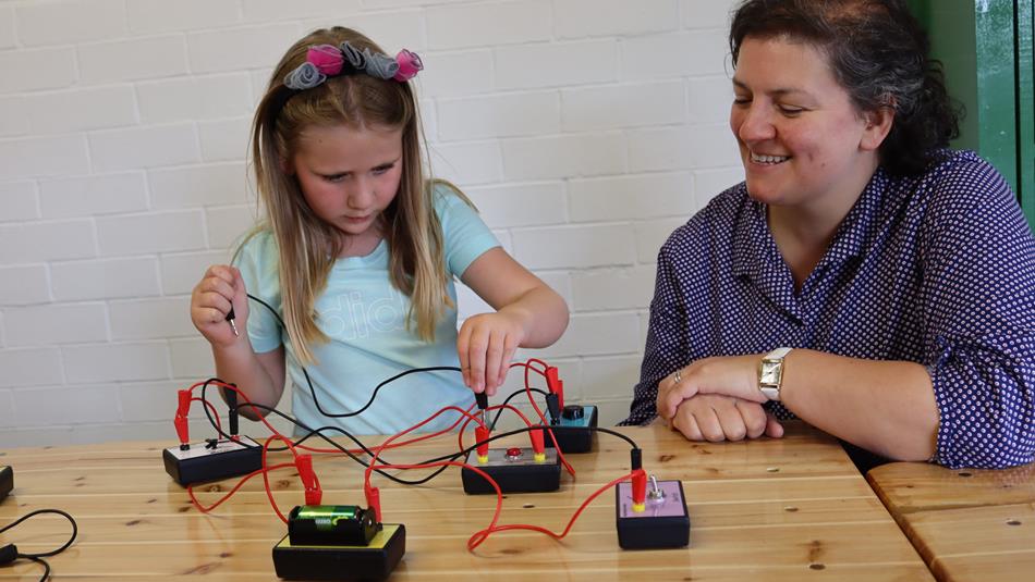 Child, sitting next to adult, engaging in science, technology, engineering and maths-related activities.