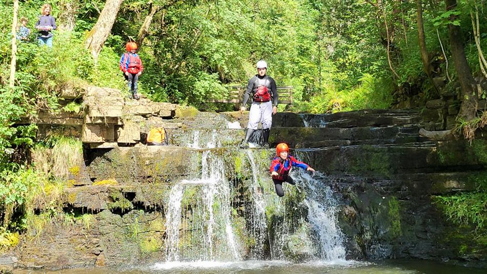 A group enjoying climbing waterfalls, navigating rocky streams and plunging into deep pools.
