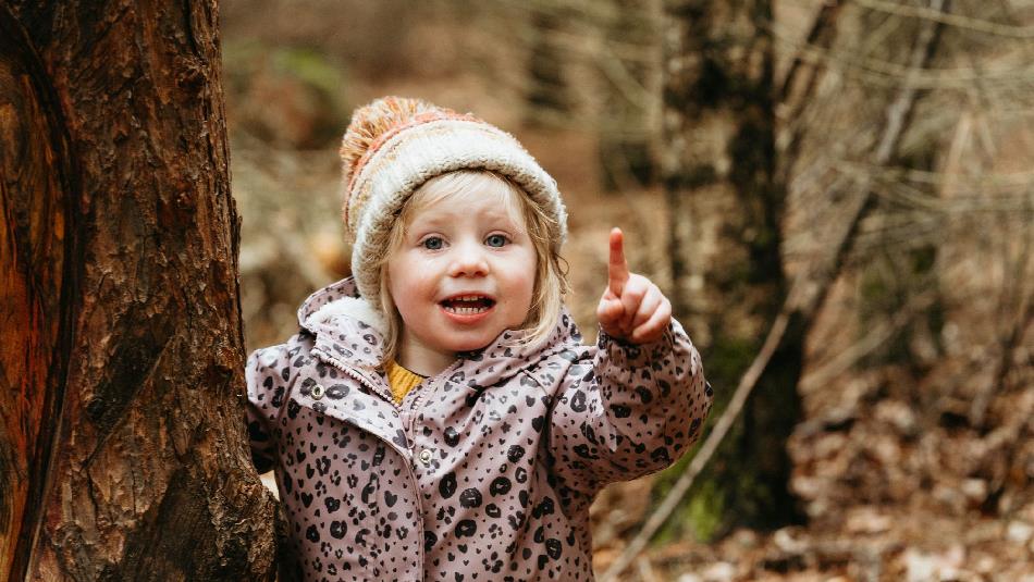 A child smiling and pointing upwards.