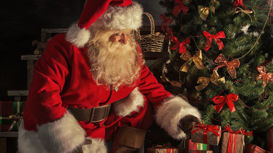 Santa placing presents under a tree.