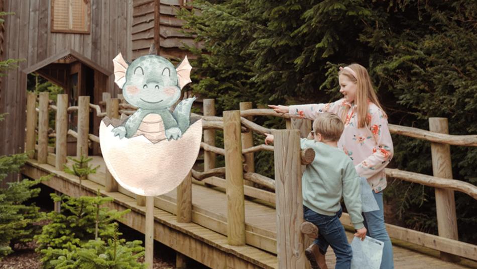 Two children in The Plotters' Forest pointing to a dragon hatching from an egg at Raby Castle.