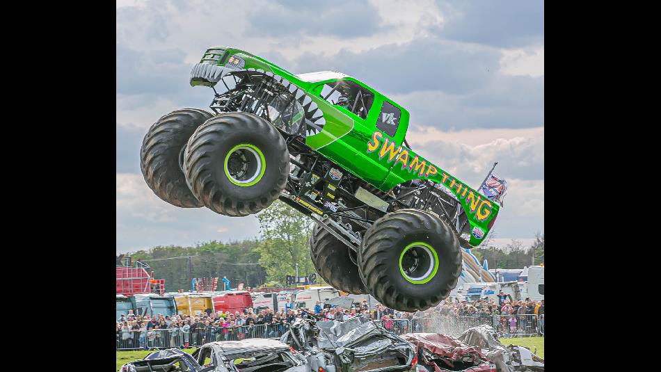 Crowds watching Monster Trucks crushing a row of cars