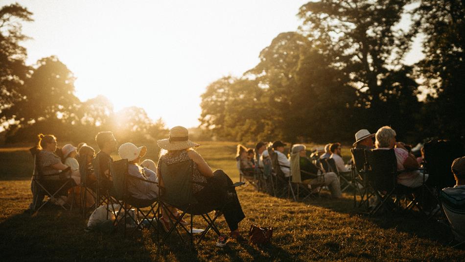 Audience enjoying an evening outdoor theatre performance at Raby Castle, Park and Gardens.