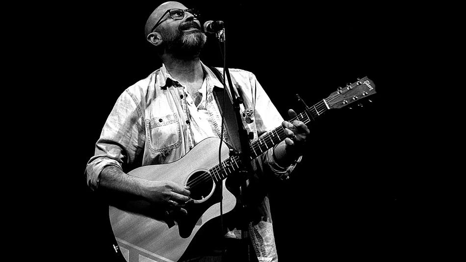 Black and white image of Steve Pledger playing guitar and singing on stage