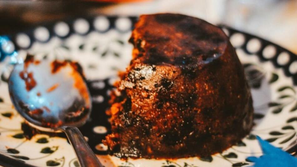 Close up view of a half eaten Christmas pudding on an ornate plate.