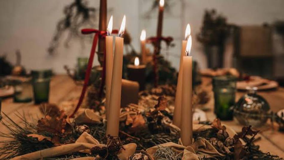 Close up of a festive table spread with lit candles and winter foliage