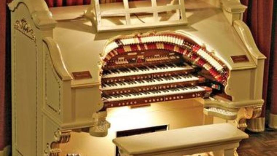 The mighty wurlitzer, an ornate piano- like instrument with a burgundy curtain in the background