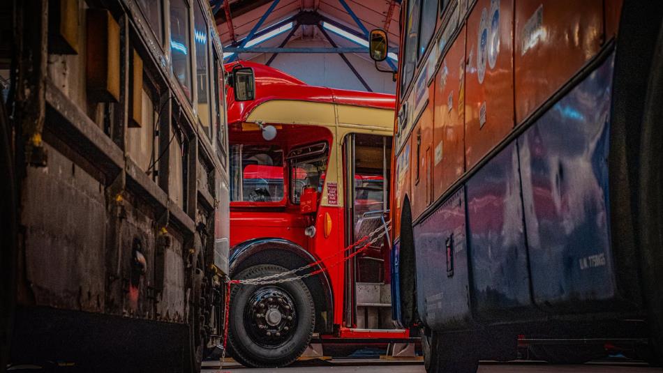 A red vintage bus parked between two others
