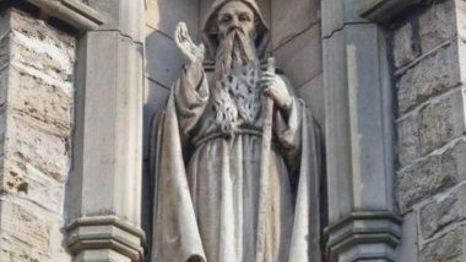 An ornate marble statue of a hooded figure connected to a church