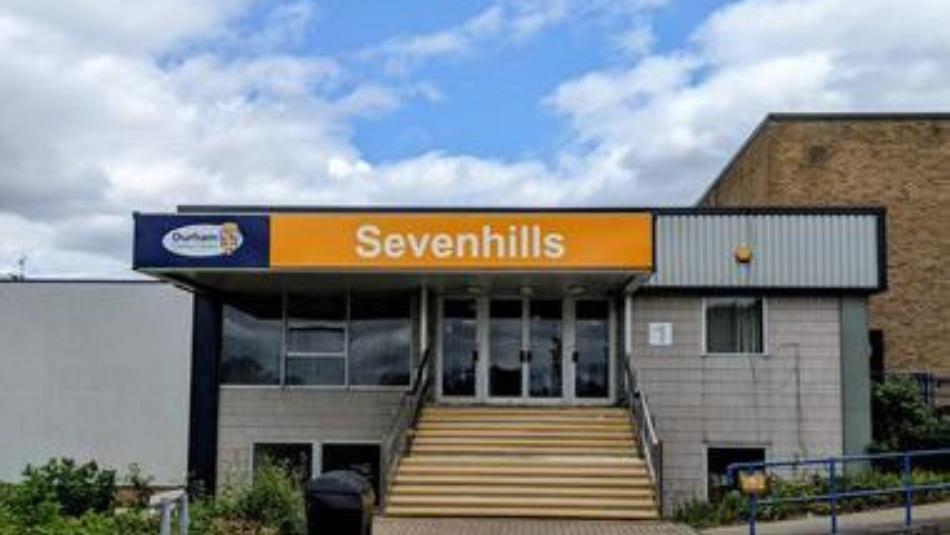 External view of a small building with a yellow sign reading Sevenhills