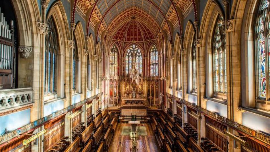 The interior of an extravagant chapel, with stained glass windows surrounding it