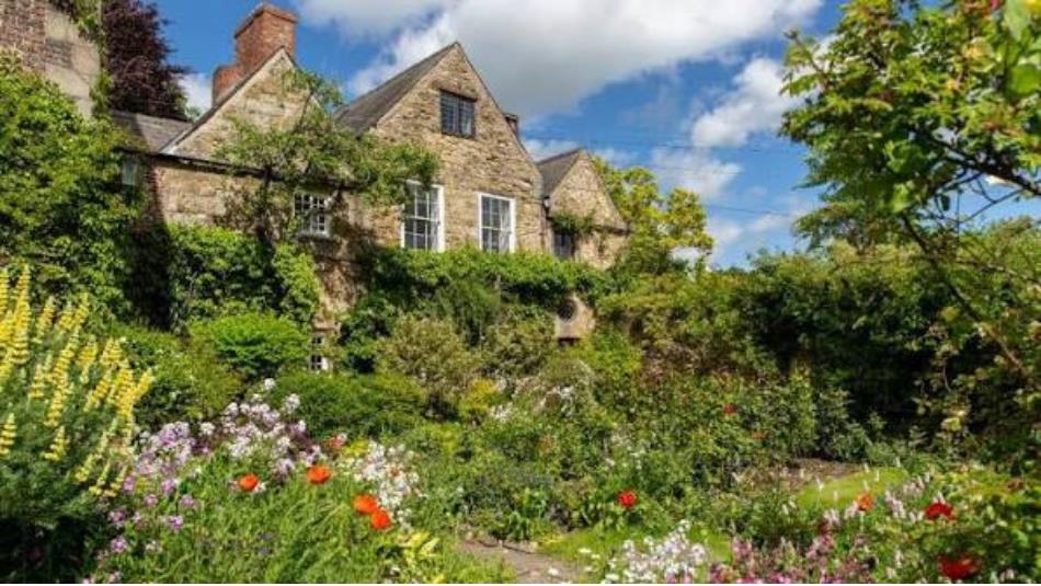 A beautiful green garden surrounds a historic stone house