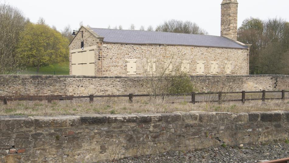 A large stone train shed surrounded by trees