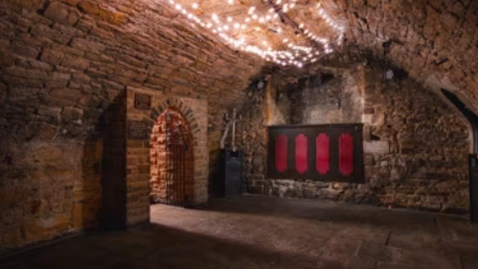 A historic stone room with low curved ceilings and fairy lights