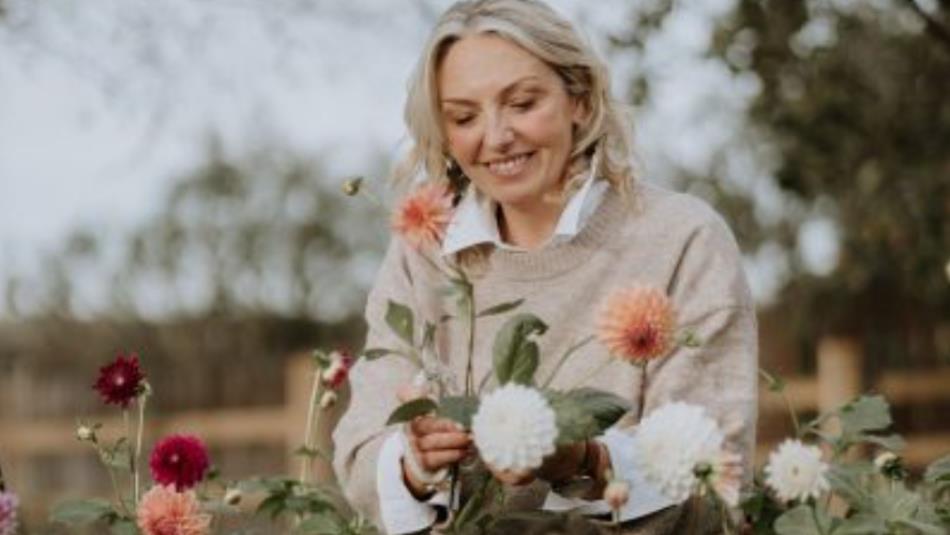 Person smiling whilst tending to colourful flowers in the garden