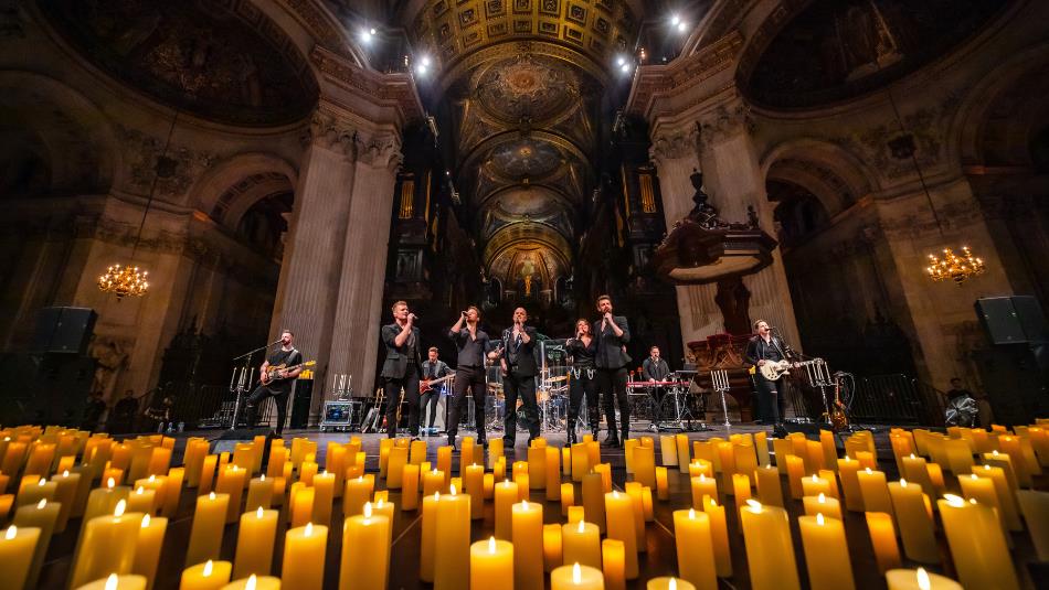 Live performers on stage in a candlelit cathedral.