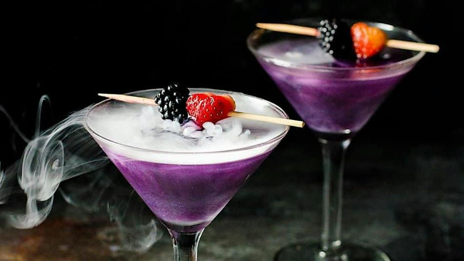 Two misty purple cocktails with berries on top
